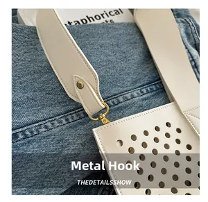 Detail of premium hardware hook and laser-cut holes on white leather bucket bag