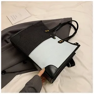 Detail of color-block tote bag with woven texture, rivets and leather corners