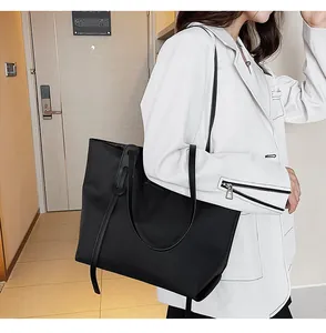 Close-up of a large black waterproof nylon tote bag styled with a professional white blazer