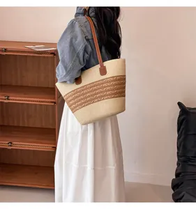 Detail of hand-woven straw tote bag with brown floral patterns and leather shoulder strap