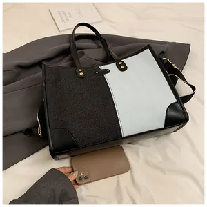 Detail of color-block tote bag with fabric paneling, leather trim and golden hardware