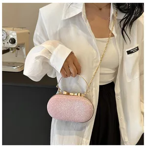 Detail of light pink glitter evening bag with golden metal bow clasp and chain strap
