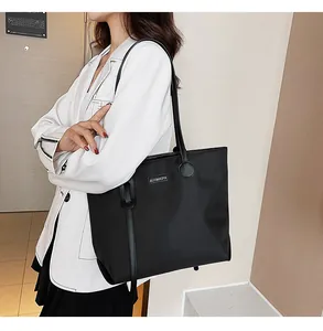 Lifestyle shot of a black waterproof nylon tote bag worn by a model in a white blazer