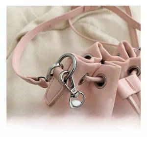 Detail view of pink leather drawstring bag with silver metal eyelets and spring hook