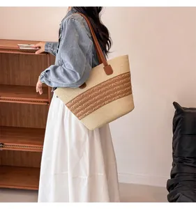 Detail of woven straw shoulder bag with dark brown leather straps and striped accents