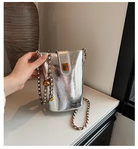 Détail du sac seau argenté métallisé avec bandoulière chaîne et boucle dorée