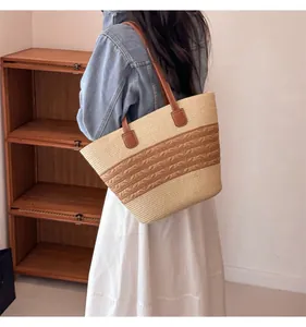 Detail of a large straw tote bag featuring beige brown weave and leather shoulder straps