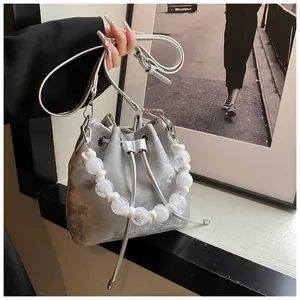 Detail of silver metallic bucket bag with oversized white pearl beaded handle and drawstring
