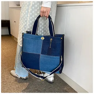 Détail d'un sac cabas en denim patchwork avec fermoir doré et bandoulière rayée