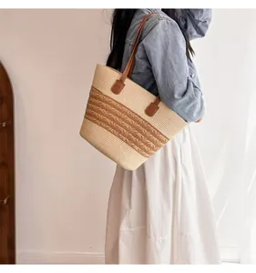 Detail of woven straw tote bag with brown leather handles and striped texture