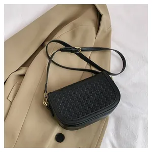 Detail of black woven leather saddle bag with gold metal hooks on a chic background