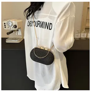 Detail of elegant black glitter evening bag with golden bow clasp and metal handle