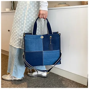Détail du sac cabas patchwork en denim bicolore avec fermoir rotatif et rivets dorés
