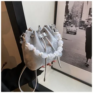 Detail of silver bucket bag featuring drawstring closure and white pearl beaded handle