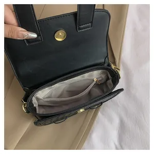 Detail of black saddle bag interior with grey herringbone lining and golden magnetic clasp