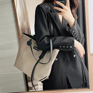 Waterproof khaki nylon tote bag with black straps in a professional mirror selfie view