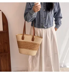 Close-up of woven straw tote bag featuring two-tone striped texture and brown leather handles