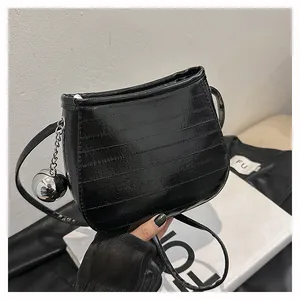 Détail du sac de selle noir brillant avec motif gaufré et breloque chaîne à boules argent