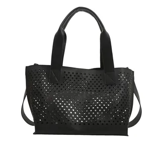 Minimalist black hollow-out tote bag with detailed laser-cut circular patterns and top handle