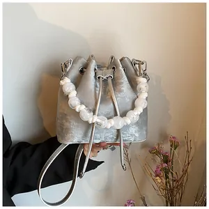 Close-up of silver-grey bucket bag with white beaded handle and drawstring closure