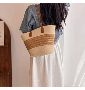 Detail of hand-woven straw tote bag with beige contrast panels and leather shoulder straps