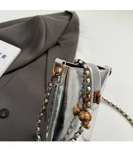 Gros plan sur le mini sac argenté avec fermoir doré et détails de bandoulière chaîne