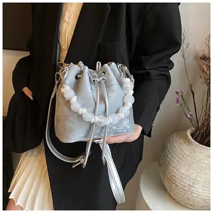 Detail of silver velvet bucket bag featuring beaded handle and drawstring closure