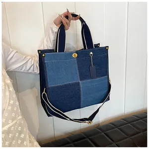 Détail du sac cabas en denim bicolore avec surpiqûres contrastées et bouton métallique