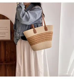 Detail of handmade straw tote bag featuring brown PU leather handles and woven wave trim