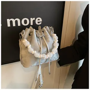 Detailed view of silver velvet drawstring bucket bag with pearl handle and metal eyelets