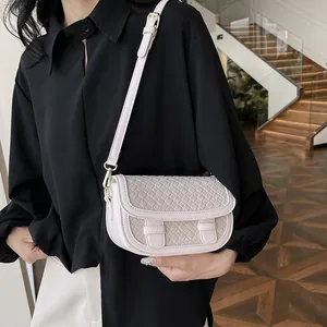 Elegant beige saddle bag with woven texture and adjustable strap on a female model