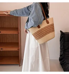 Detail of hand-woven straw tote bag with brown wave pattern and leather shoulder straps