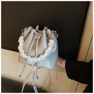 Detailed view of silver drawstring bucket bag with shiny metallic finish and bead handle