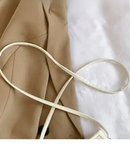 Gros plan sur la longue bandoulière lisse avec coutures fines du sac seau crème