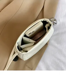 Vue intérieure du petit sac seau blanc avec fermoir boule argenté et son espace de rangement