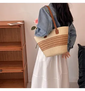 Detail of woven straw tote bag with brown leather straps and dual-tone texture
