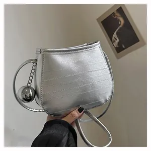 Gros plan du sac seau argenté métallisé avec texture gaufrée et breloque boule en métal