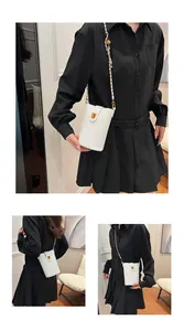 Détail d'un sac à téléphone vertical en cuir blanc avec fermoir doré et bandoulière chaîne