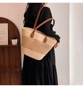Close-up of handmade straw tote bag with brown leather handles and woven texture details