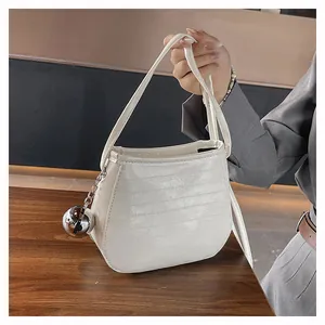 Vue détaillée du sac seau blanc avec texture cuir et grand pendentif boule en argent