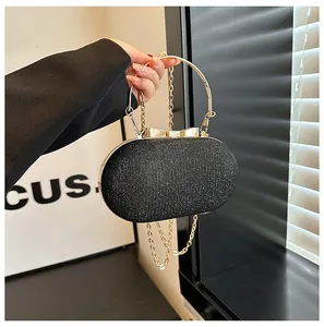 Detail of black sequined evening bag with gold bow clasp and ring handle held by model