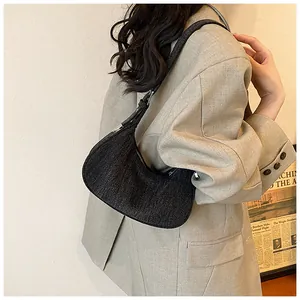 Close-up of a crescent-shaped dark denim hobo bag with adjustable strap and silver metal buckle