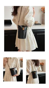 Détails d'un mini sac seau noir avec fermoir doré et bandoulière en chaîne tressée cuir