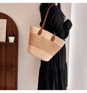 Close-up of woven straw tote bag with brown leather straps and striped texture