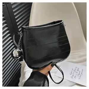 Détail du sac seau noir en similicuir brillant avec pendentif boule argentée et couture
