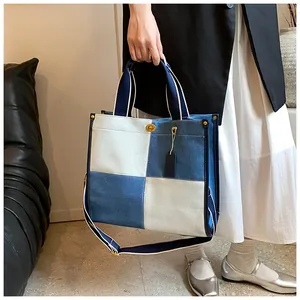 Détail du sac cabas en denim bicolore avec fermoir doré et bandoulière tissée