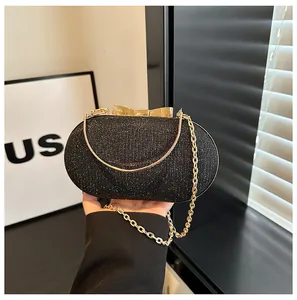 Macro view of black glitter evening clutch featuring a gold bow clasp and metal chain strap