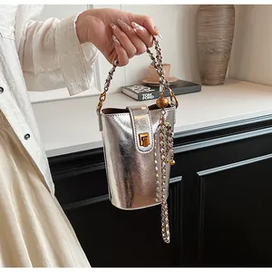 Détail du sac seau argenté montrant la texture plissée brillante et le fermoir doré