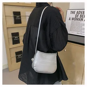 Détail du sac bandoulière argenté demi-lune avec texture gaufrée et breloque sphère en métal
