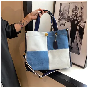 Détail du sac cabas en denim avec fermoir rotatif en métal et étiquette en cuir bleu